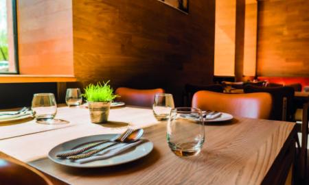 Imagen de una mesa de restaurante con vasos, platos y cubiertos